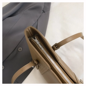 Detail of silver metal zipper and lychee pattern leather on brown tote bag