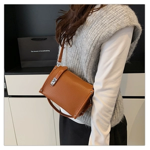Close-up of brown lychee grain leather crossbody bag with silver rotating lock closure