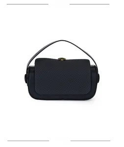 Detail of black leather handbag featuring an elegant gold flower-shaped metal clasp