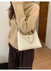 Détail du sac beige matelassé avec chaîne et boucle argentée porté à l'épaule