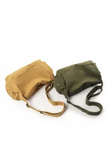 Detail view of washed canvas messenger bags in ginger and army green with adjustable straps