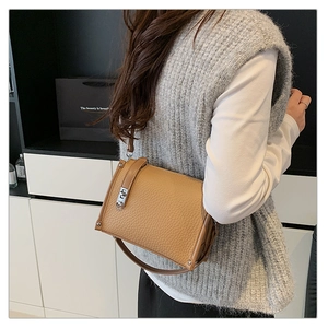 Detail of caramel leather crossbody bag featuring silver rivets and metallic turn-lock