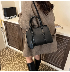Détail du sac à main en cuir grainé noir avec poignées et bandoulière réglable amovible