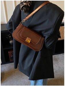 Detailansicht einer braunen Baguette-Tasche aus Leder mit goldener quadratischer Schnalle