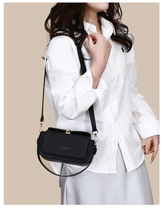 Detail of black woven texture flap on shoulder bag with elegant gold metal clasp