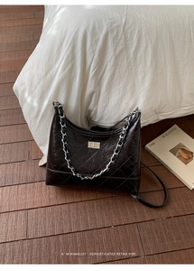 Détail d'un sac à bandoulière en cuir matelassé marron foncé avec chaîne et fermoir en métal
