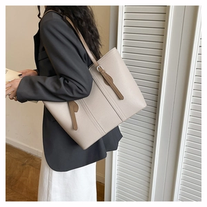 Detail view of large beige tote bag with litchi texture and brown leather shoulder straps