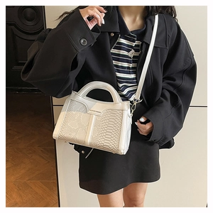 Detailed view of the off-white faux snake skin texture and rigid circular handle of the bag