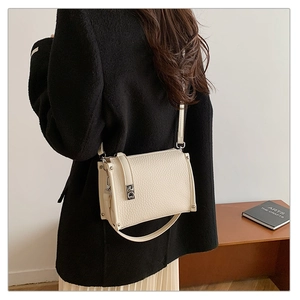 Detail shot of the cream white shoulder bag featuring textured faux leather and metal studs