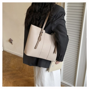 Detailed close-up of ivory tote bag with lychee texture and buckle detail on shoulder strap