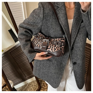 Close-up of leopard print shoulder bag with metallic buckle details on grey blazer