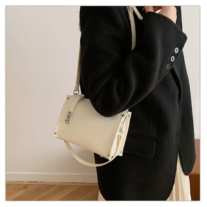 Elegant cream textured leather underarm bag with vintage metal clasp and rivet details