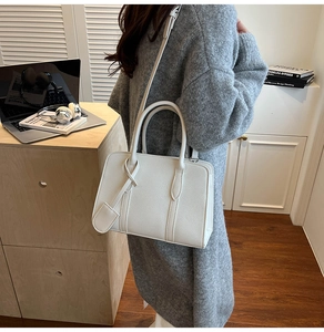 Détail du sac cabas blanc à motif litchi porté avec un pull en maille grise élégant