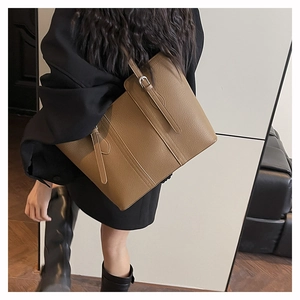 Detail of a large brown pebble leather tote bag with vertical straps and silver buckles