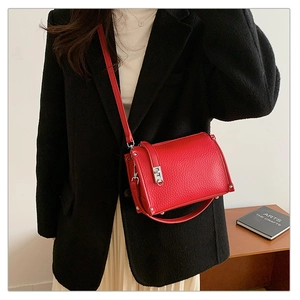 Detail of red pebbled leather shoulder bag with silver clasp on a black blazer outfit