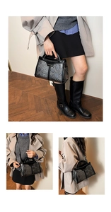 Detail of snakeskin textured crossbody bag with glossy black trim and top handle design