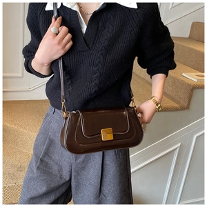 Dunkelbraune Baguette-Tasche aus Mattleder mit goldener Schnalle am Modell
