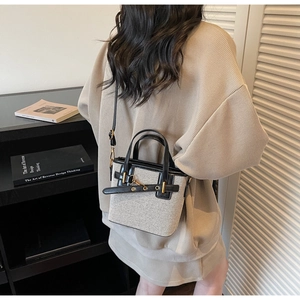 Detail shot of the beige canvas handbag with black leather trim and gold hardware accents