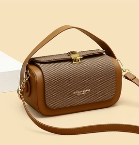 Detailed side view of caramel brown leather handbag with woven texture and gold shell buckle