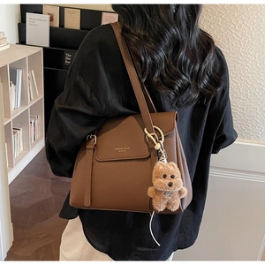 Détail du sac cabas marron foncé grainé avec charm d'ours porté à l'épaule