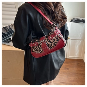 Detail of leopard print shoulder bag featuring red leather straps and silver buckles
