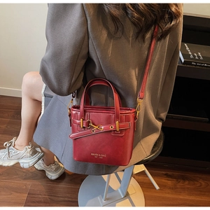 Close-up of a burgundy vintage leather bucket bag with top handle and Maven & Chic logo