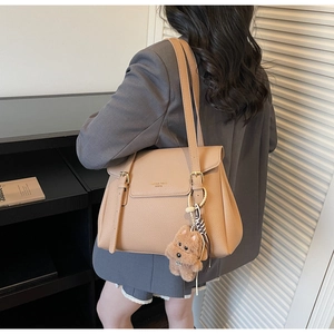 Detail of light brown lychee grain tote bag with decorative straps and teddy bear charm