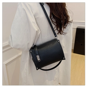 Detail of black pebbled leather texture with silver hardware and adjustable strap on a crossbody bag