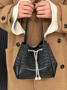 Black woven leather bucket bag with white pearl drawstring tassels and silver metal eyelets