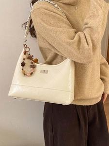 Sac baguette crème matelassé avec bandoulière chaîne et breloque porté par le mannequin
