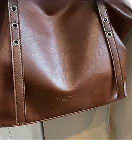 Detail der dunkelbraunen Leder-Shopper-Textur mit Metall-Öse am Schultergurt-Design