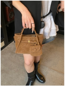 Close-up of brown suede bucket bag with mini pouch and gold ring metallic details