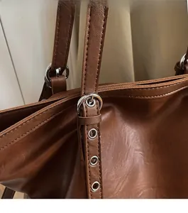Details einer dunkelbraunen Ledertasche mit silbernen Metallbeschlägen und Riemen