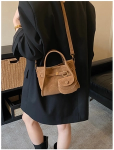 Detailed view of a brown suede bucket bag with round coin purse and gold hardware detail