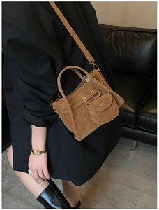 Close-up of brown matte suede bucket bag with gold hardware and adjustable strap