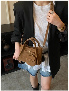 Close-up of brown suede bucket bag with decorative mini pouch and metal buckle details