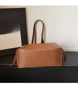 Detail der karamellbraunen Vintage-Tasche mit feinen Nähten und goldenem Fashion-Logo