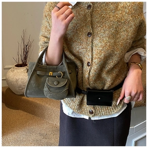 Detail of dark green velvet bucket bag with mini black waist pouch on a model's outfit