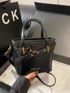 Glossy black leather bucket bag with top handle and gold hardware shown with packaging