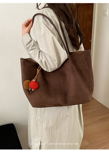 Large brown suede tote bag with a minimalist retro style and decorative pom-pom.