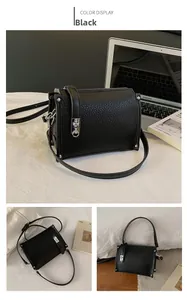 Detail of black lychee grain leather crossbody bag with silver buckle on a desktop