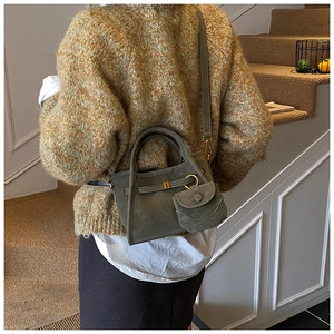 Detail view of a dark green bucket bag with a small matching pouch and gold metal hardware