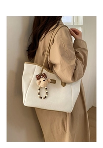 Détail du cabas en toile avec bordure en cuir marron et breloque ours en peluche mignonne