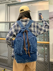 Vintage washed blue denim backpack with drawstring closure and double front zip pockets