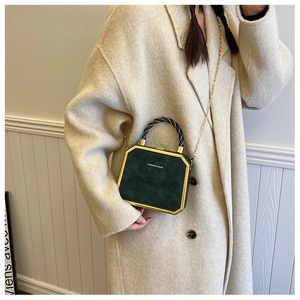 Detail of dark green octagonal box bag with gold metal corners and braided handle
