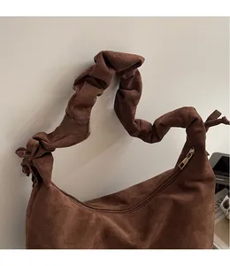 Detail of vintage brown suede hobo bag featuring a knotted pleated shoulder strap and metal zipper