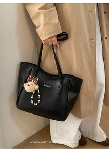 Détail du sac cabas en similicuir noir avec breloque d'ours et logo élégant