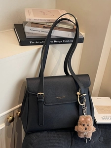 Minimalist black pebble leather tote bag with gold buckles and brown plush bear charm