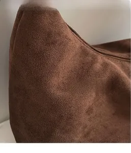 Close-up of brown suede fabric texture and smooth zipper detail on casual crossbody bag