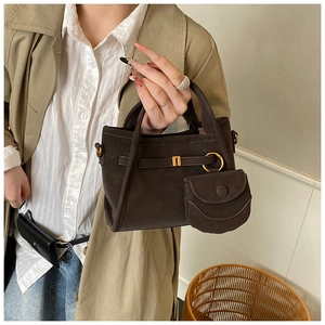 Detail of dark brown canvas bucket bag with mini pouch and gold hardware on model
